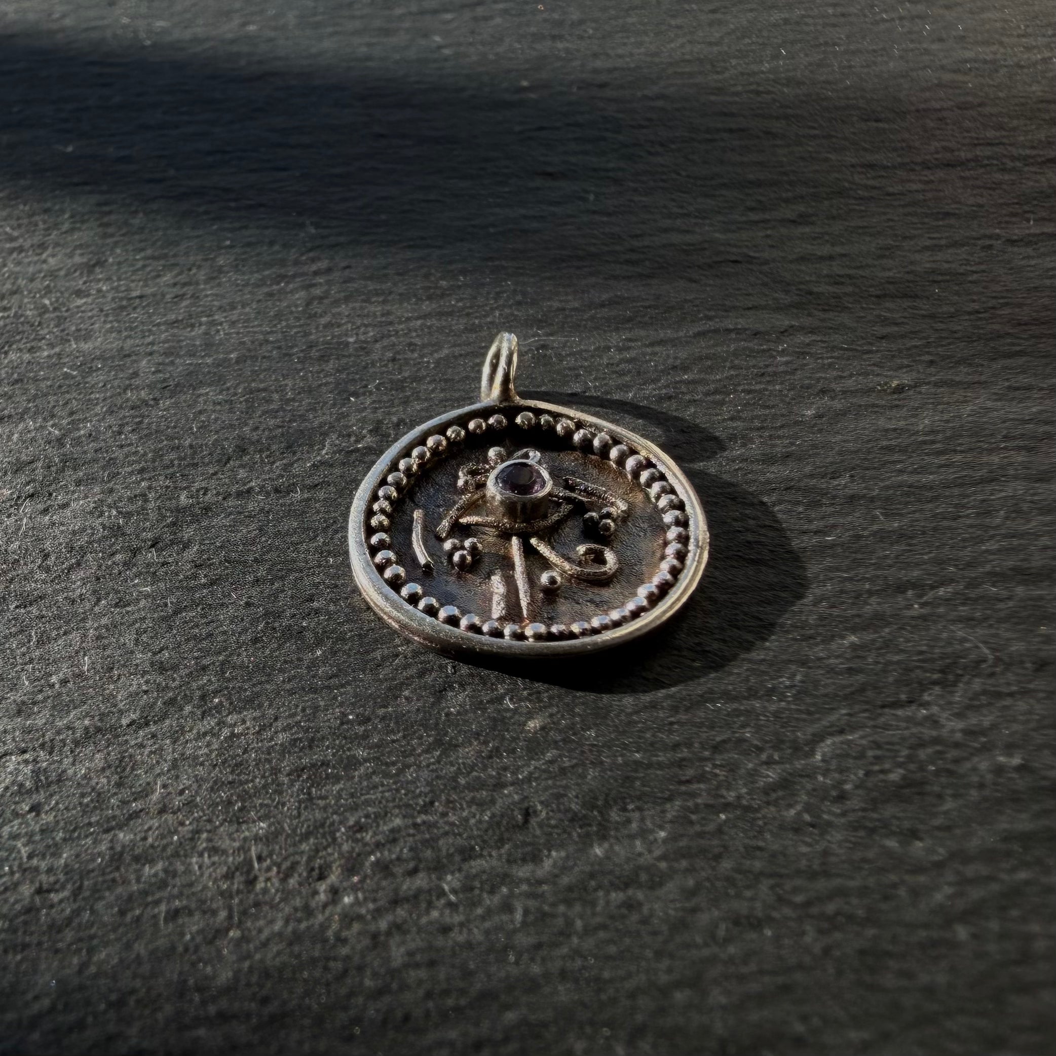 Side profile of sterling silver Eye of Horus talisman pendant showing raised detailing