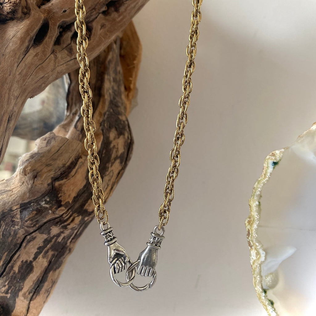 interlocking silver hands with gold chain