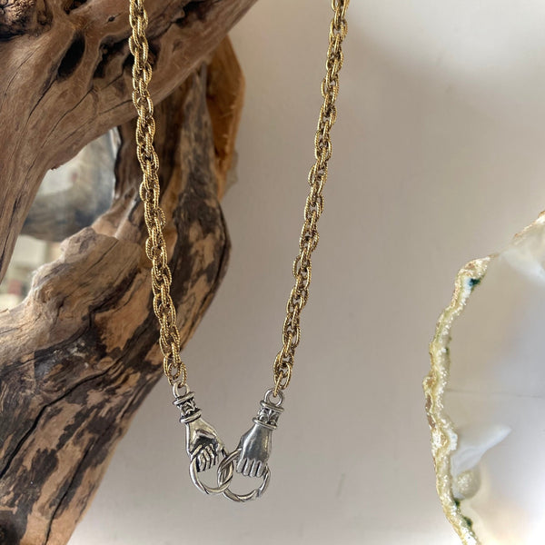 interlocking silver hands with gold chain