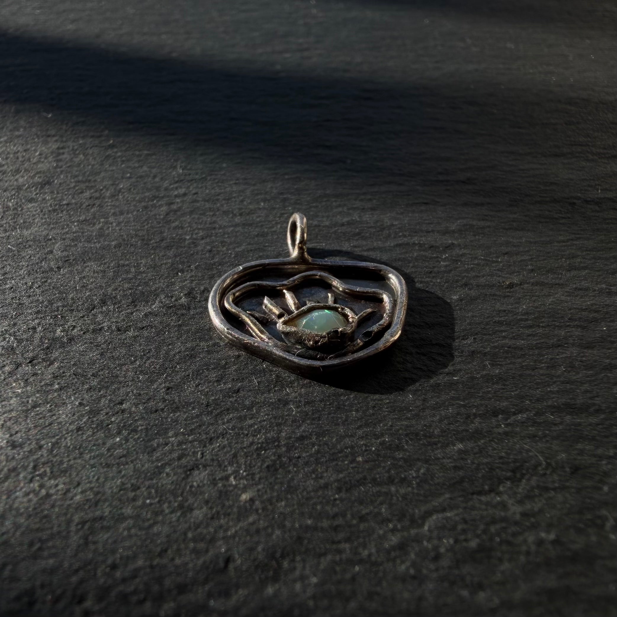 Side detail of sterling silver evil eye shell pendant with opal gemstone