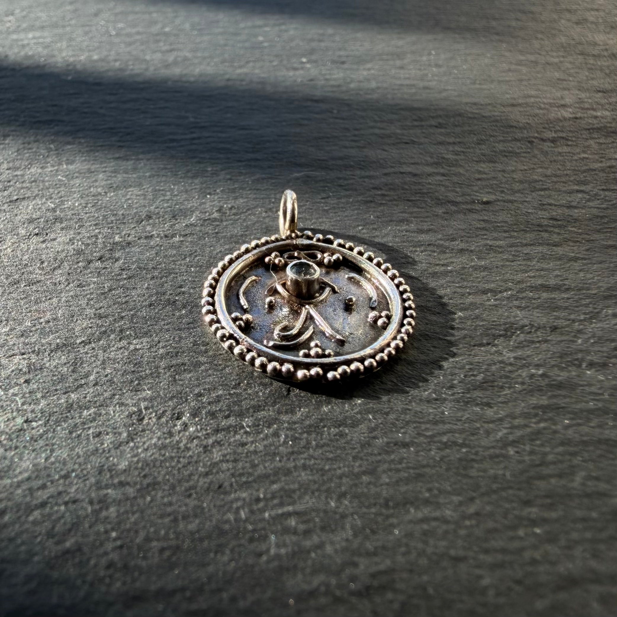 Side profile of oxidised sterling silver Eye of Ra talisman pendant with aquamarine