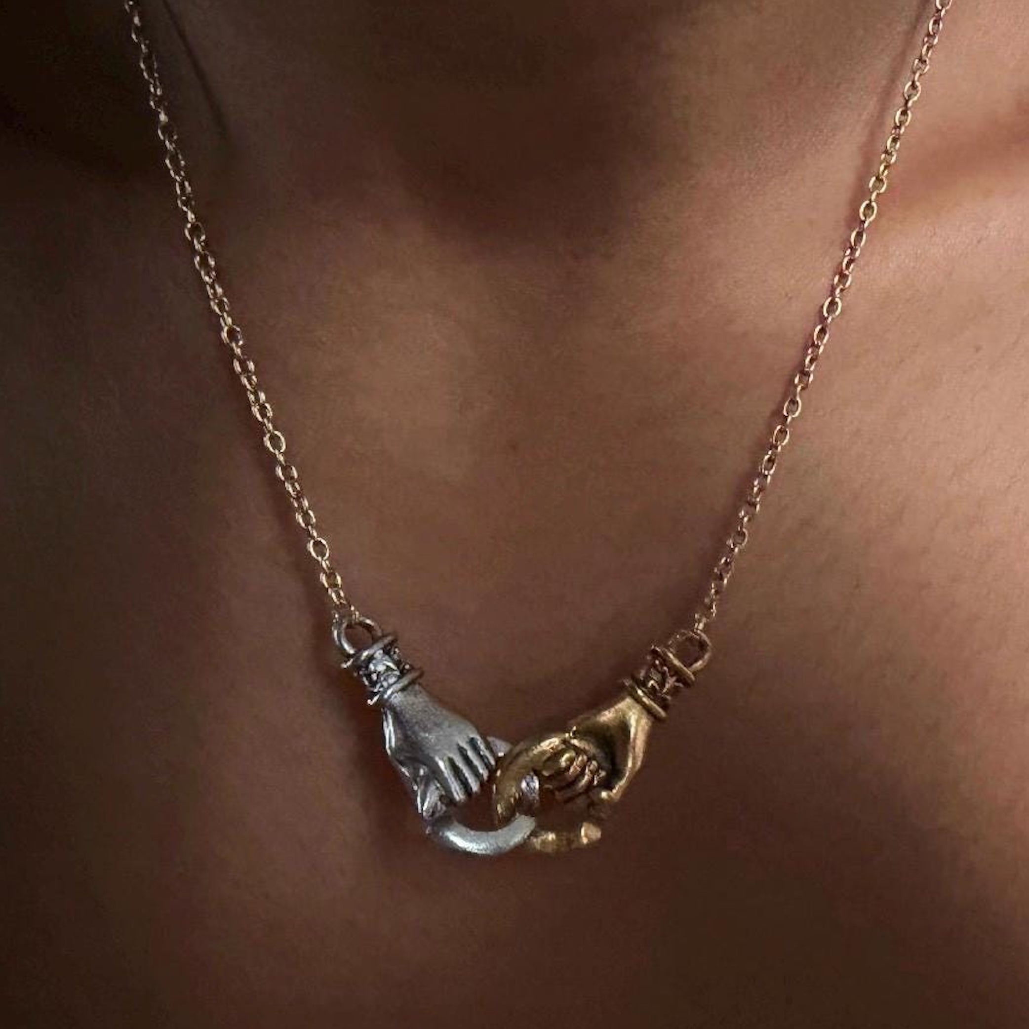 interlocking hands mixed metal necklace