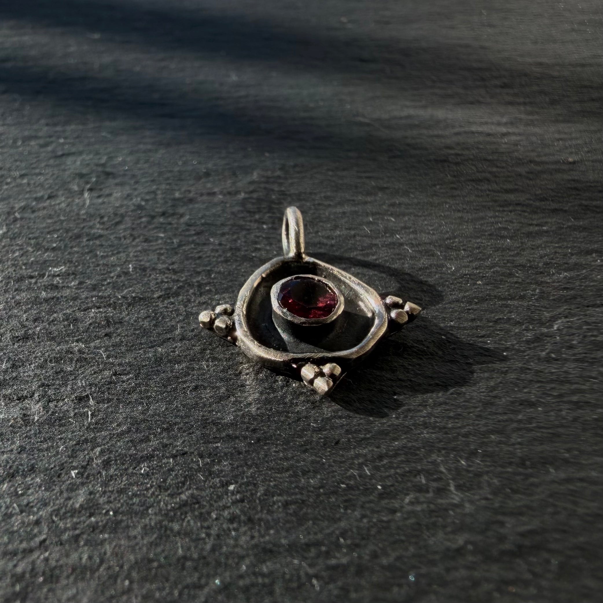 Side detail of sterling silver evil eye pendant with pink tourmaline gemstone
